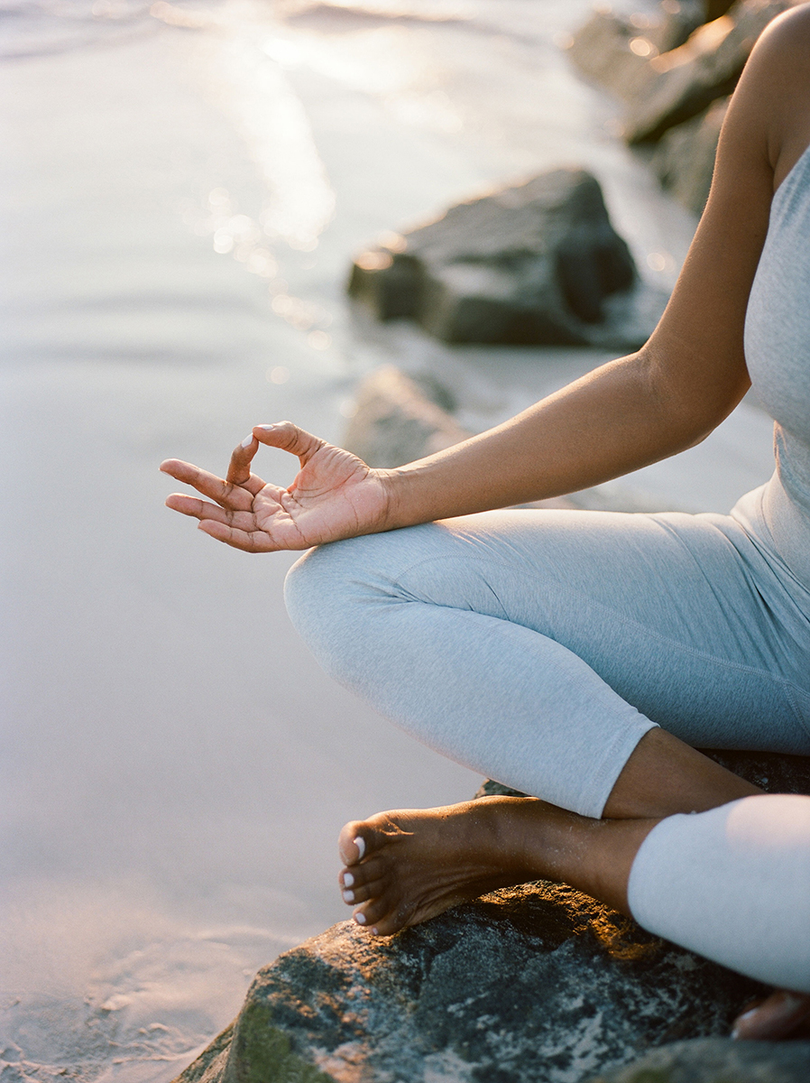 Woman practicing a sitting Kundalini yoga pose, making mudra with her hands